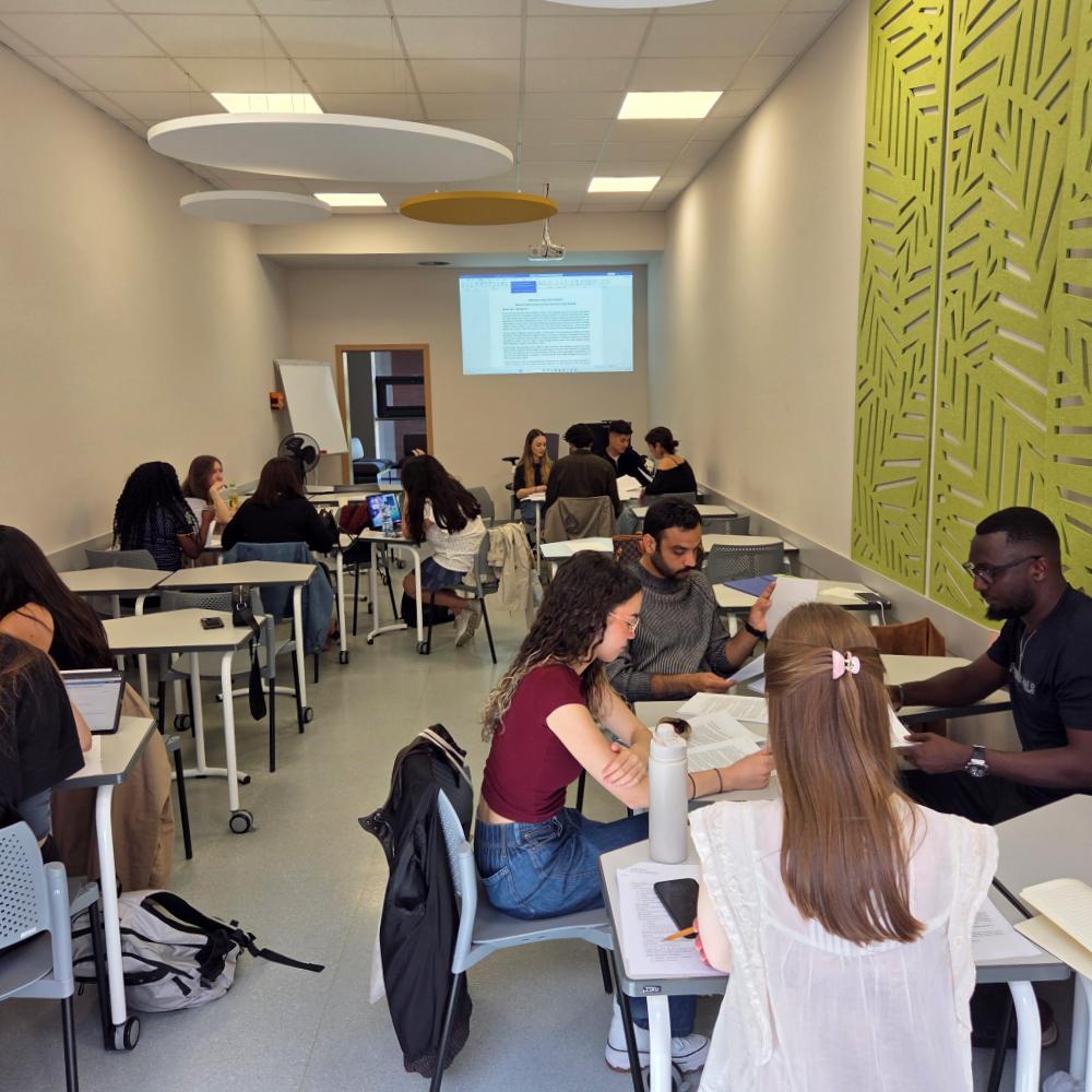 Gorups of international students work on projects in a classroom