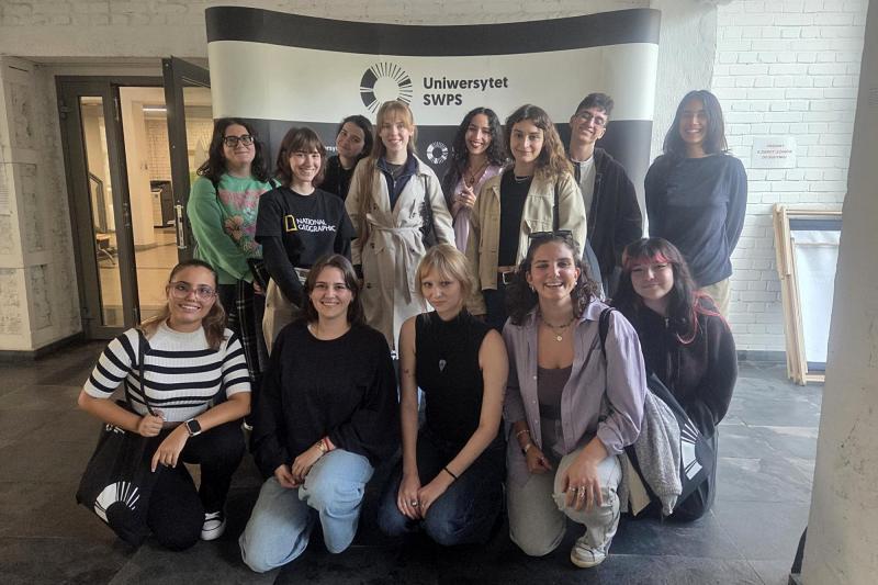 Group photo of students attending The Art of Emotions course posing in front of USWPS photo wall in Katowice